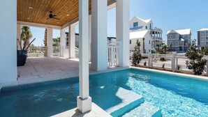 A modern pool area with a wooden ceiling and white columns, surrounded by a white fence and palm trees. - Gulf Views | Private Pool | LSV | Elevator (Santa Rosa Beach)
