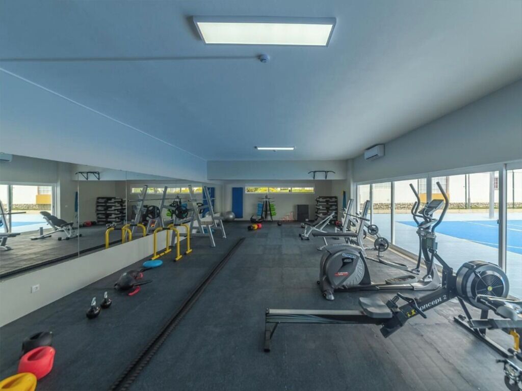 A gym with exercise equipment, mirrors, and a view of the outdoors.