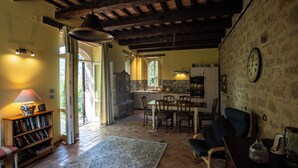 Een landelijk interieur met een eethoek, keuken en een boekenplank.