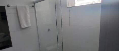 A modern bathroom with a toilet, sink, and glass shower enclosure.