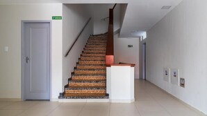 A staircase with a wooden handrail and patterned steps leading to a landing. - GoldMen Express Campos dos Goytacazes (Campos)
