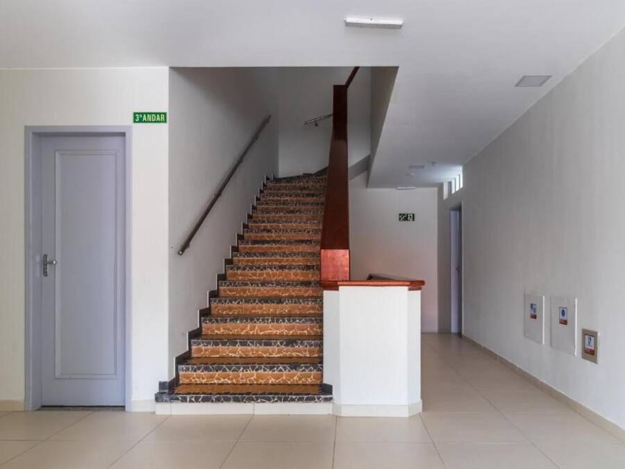 A staircase with a wooden handrail and patterned steps leading to a landing.