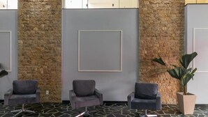 A lobby with three grey armchairs, a stone wall, and a large potted plant. - GoldMen Express Campos dos Goytacazes (Campos)