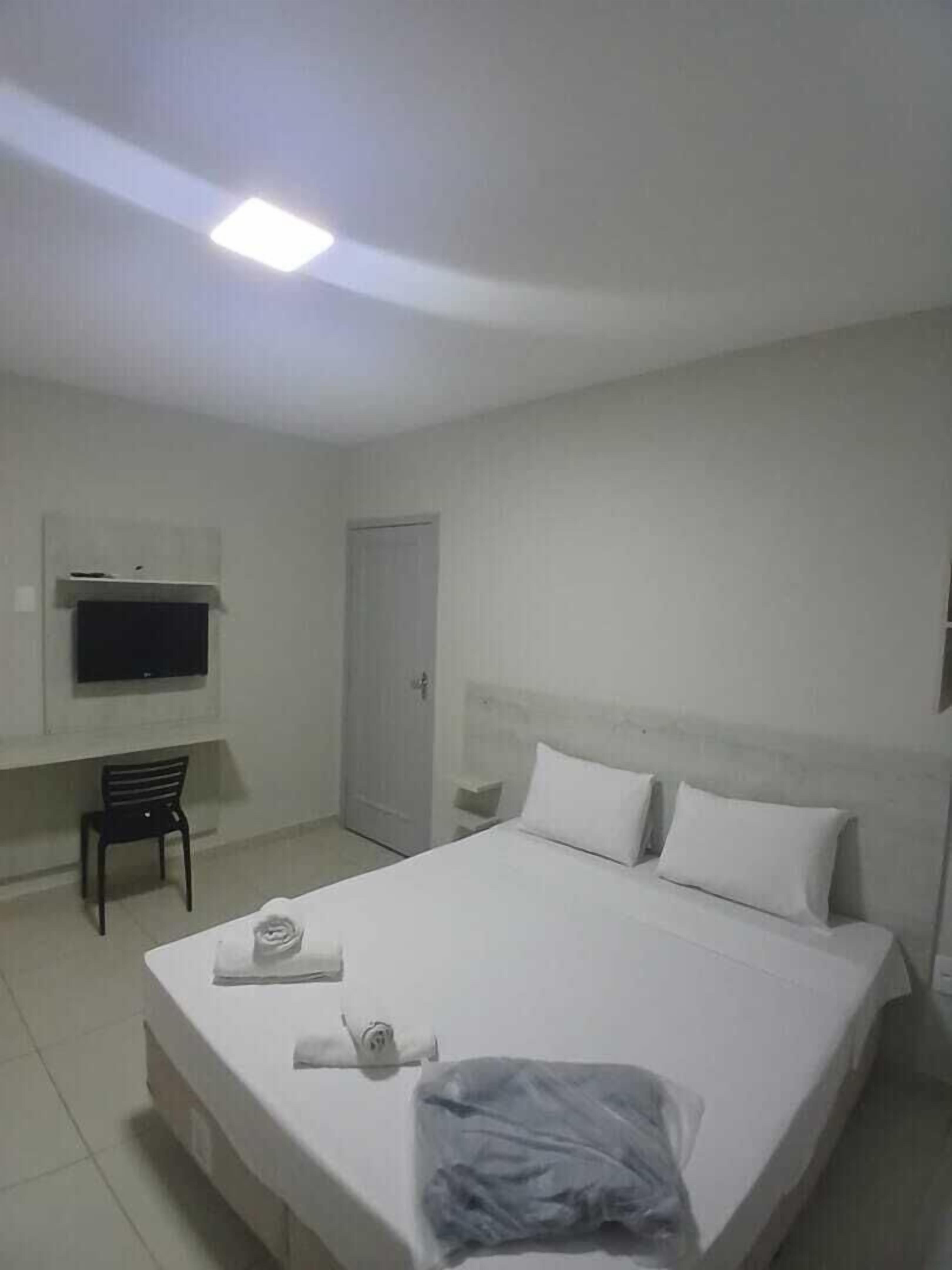 A hotel room with a bed, a television, a chair, and a door.