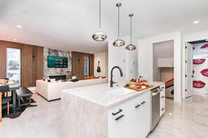 A modern kitchen with a marble countertop, a built-in sink, and a breakfast bar. - Nashville rooftop hot tub house with disco room, sleeps 12, family getaway (Nashville)