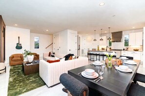 Ein modernes Wohnzimmer mit einer Couch, einem Couchtisch und einem Essbereich mit Tisch für vier Personen.