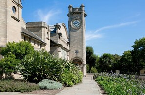A historic building with a clock tower, a paved pathway, and lush greenery. - Modern Garden 1BDR Flat in Forest Hill Honor Oak (Greater London)