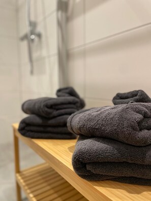 Une salle de bain avec une étagère en bois où sont pliées des serviettes.