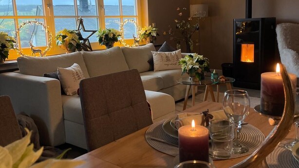 A cozy living room with a dining area, a fireplace, and a view of the sea through large windows. - DottiesPlace: A cozy vacation rental with sweeping views of the entire area (Winterberg)
