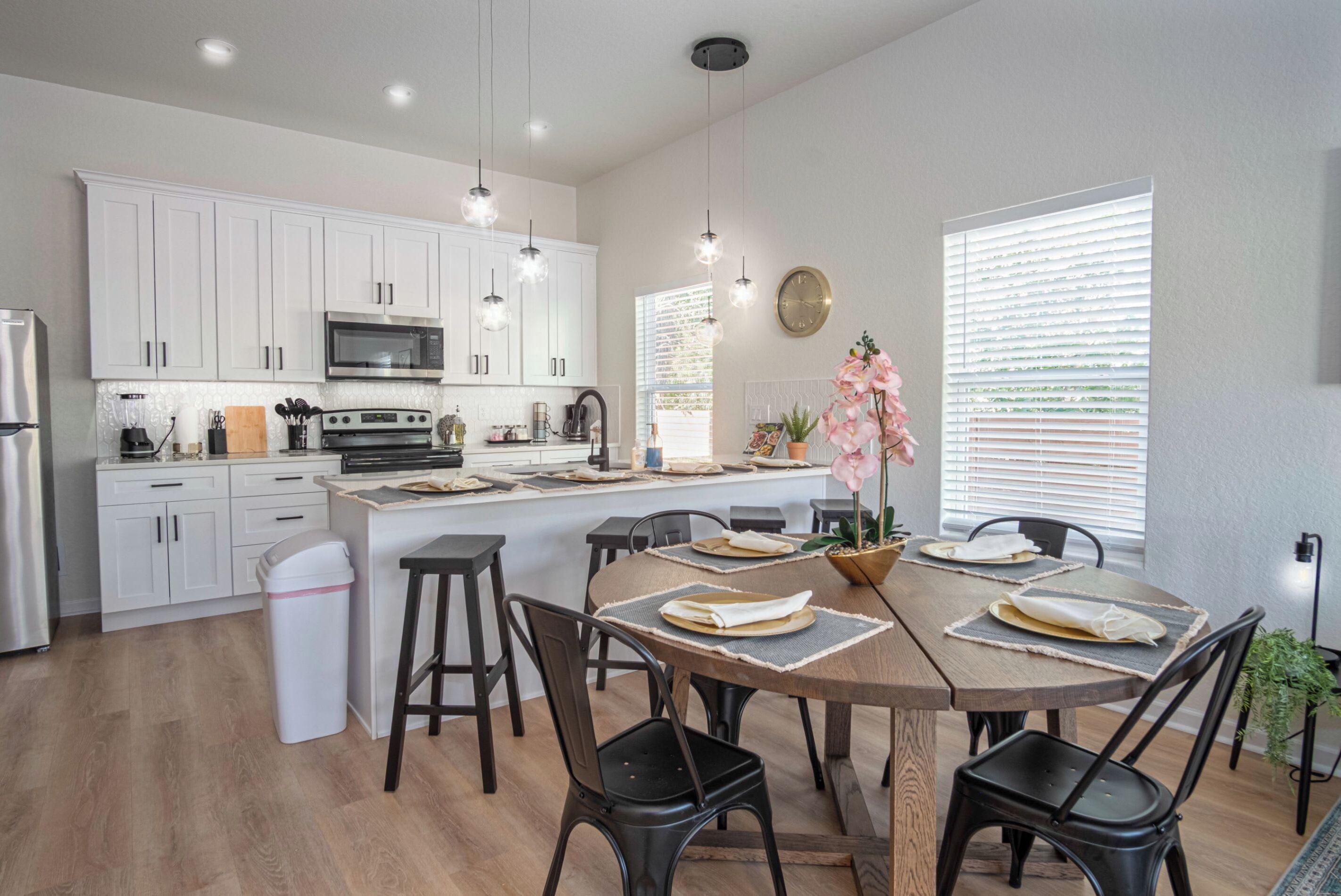 A modern kitchen with white cabinets, a central island, and pendant lighting.
