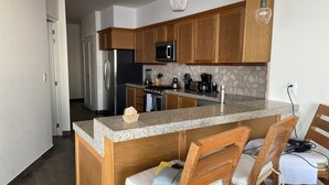 Eine moderne Küche mit Holzausstattung, Granit Arbeitsplatten, Edelstahlgeräten und einem Essbereich mit Holzkästen.