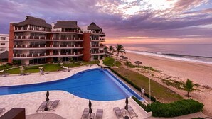 Un hotel con piscina, vistas a la playa y varios balcones.