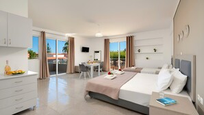 A modern hotel room with a large bed, a desk, and a balcony with a table and chairs. - The Garden Studio Pool View (Chania)