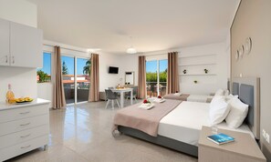 A modern hotel room with a large bed, a desk, and a balcony with a table and chairs. - The Garden Studio Pool View (Chania)
