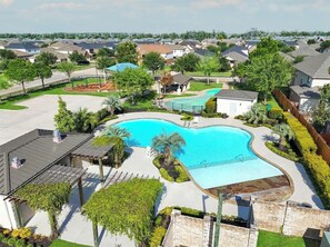 Un quartier résidentiel doté d’une piscine, entouré de verdure et de maisons.