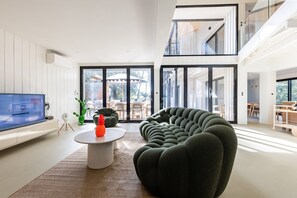 Ein modernes Wohnzimmer mit einem Flachbildfernseher, einem runden Couchtisch und einem außergewöhnlichen grünen Sofa.