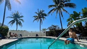 A swimming pool with clear blue water, surrounded by palm trees and a white fence. - Oceanfront Studio · South of Fifth + Beach Perks (Miami Beach)