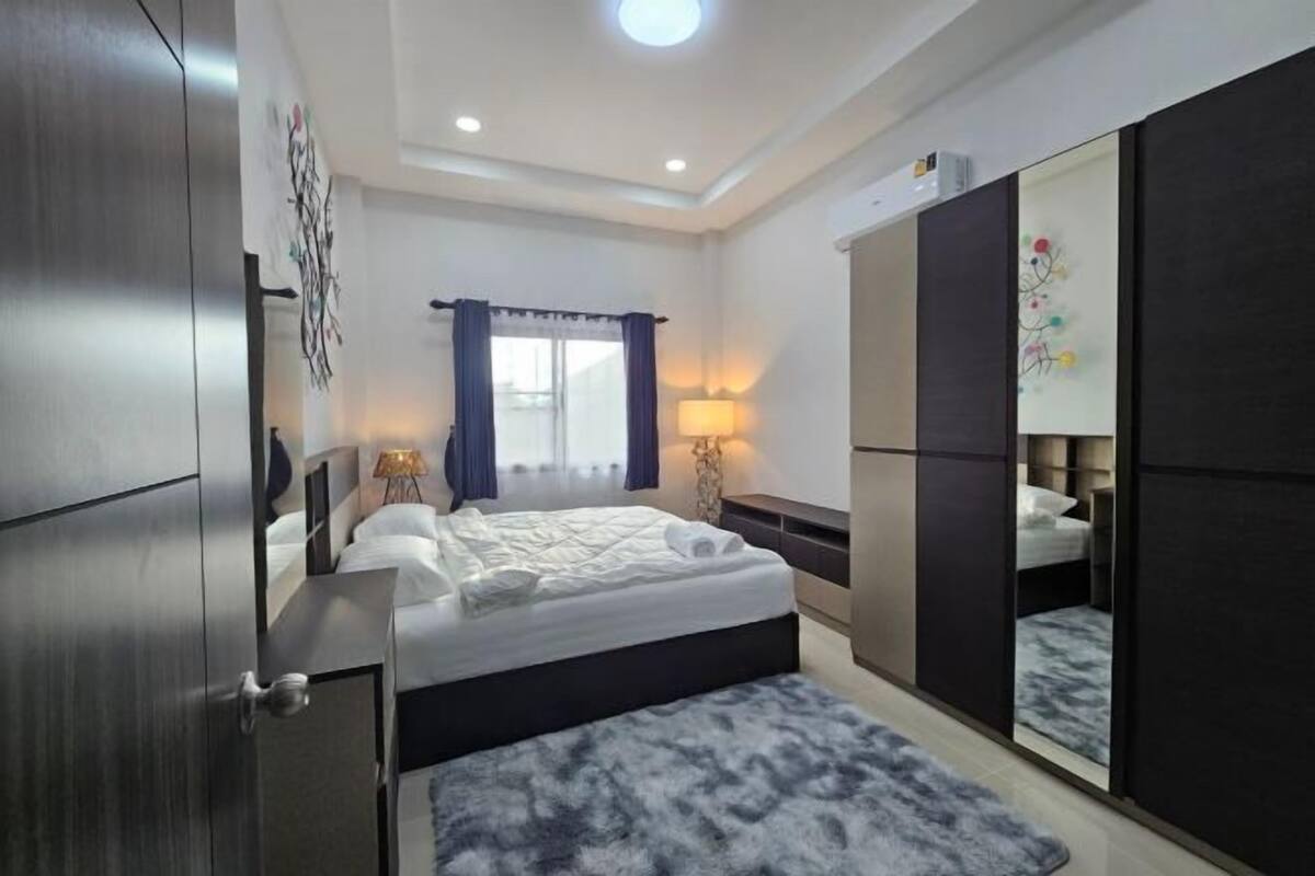Una habitación de hotel moderna con una cama grande, un armario, un escritorio y un espejo.