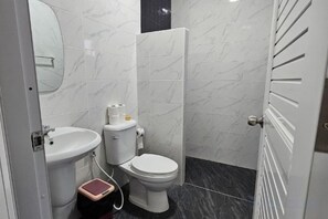 Een badkamer met toilet, wastafel en spiegel.