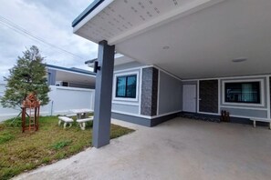 Een modern huis met een overdekt terras, een kleine tuin en een duidelijke deur.