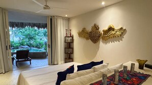 A bedroom with a bed, pillows, a decorative rug, and a view of a garden through a sliding door. - Luxury Oceanfront At Majahua (Troncones)