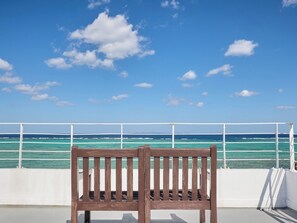 A wooden bench with a view of the ocean and a clear sky. - Nonsmoking Wave301 / Kunigami County Okinawa (Kunigami County)