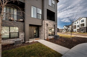 A modern multi-story residential building with a stone facade, large windows, and a well-maintained lawn. - Peaceful Mtn Retreat - Sleeps 10 - Hot Tub, Family Fun (Mountain Green)