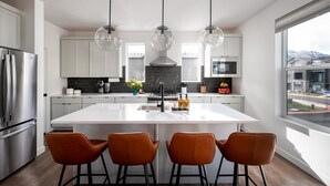 Una cocina moderna con una isla central, electrodomésticos de acero inoxidable y vistas al exterior.