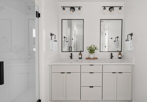Une salle de bain moderne avec deux lavabos, un miroir et une plante en pot.