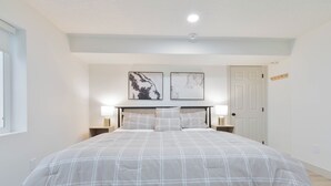 Un dormitorio con una cama grande, dos lámparas de pared y dos cuadros enmarcados sobre la cama.