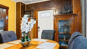 Zona pranzo con tavolo in legno, sedie e un centrotavola decorativo con un'orchidea.