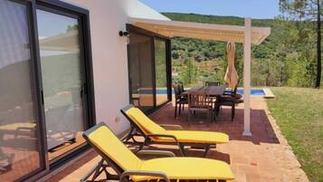 A patio with yellow lounge chairs, a table, and a pergola.