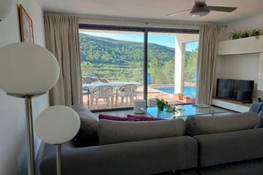 A living room with a sofa, TV, and a glass table. There is a balcony with a pool and outdoor seating. - Casa Diospiro (Sao Bartolomeu de Messines)