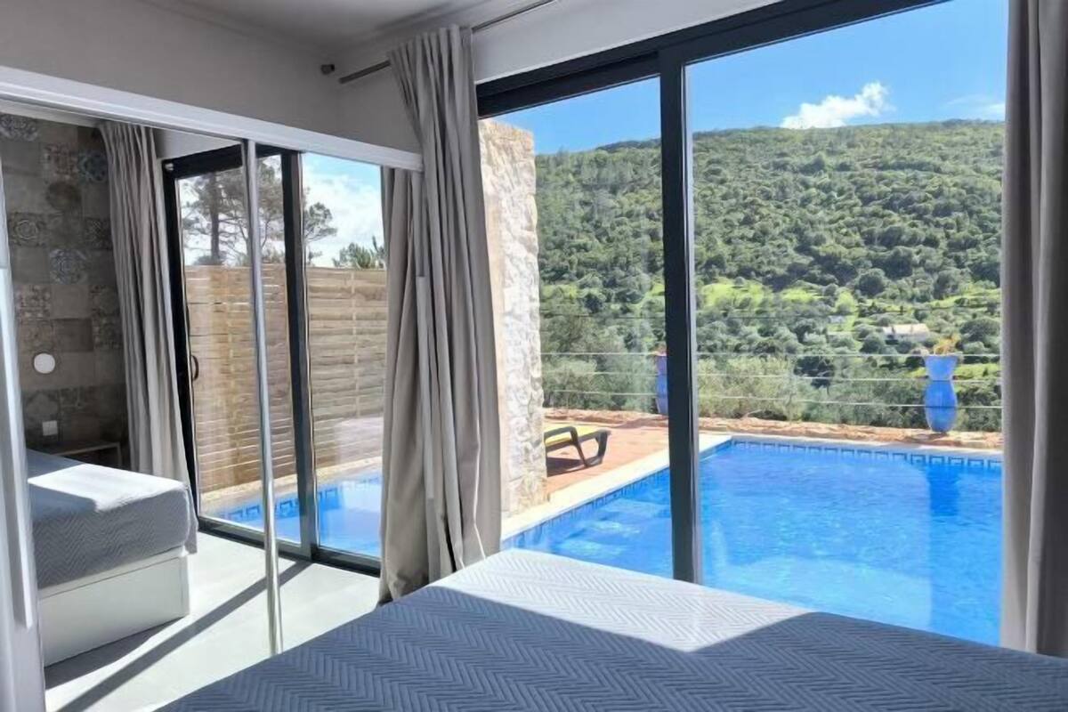 A bedroom with a view of a swimming pool and a mountain.
