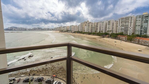 Blick auf einen Strand vom Balkon mit Geländer, mit Blick auf einen Sandstrand und eine Reihe hoher Gebäude.
