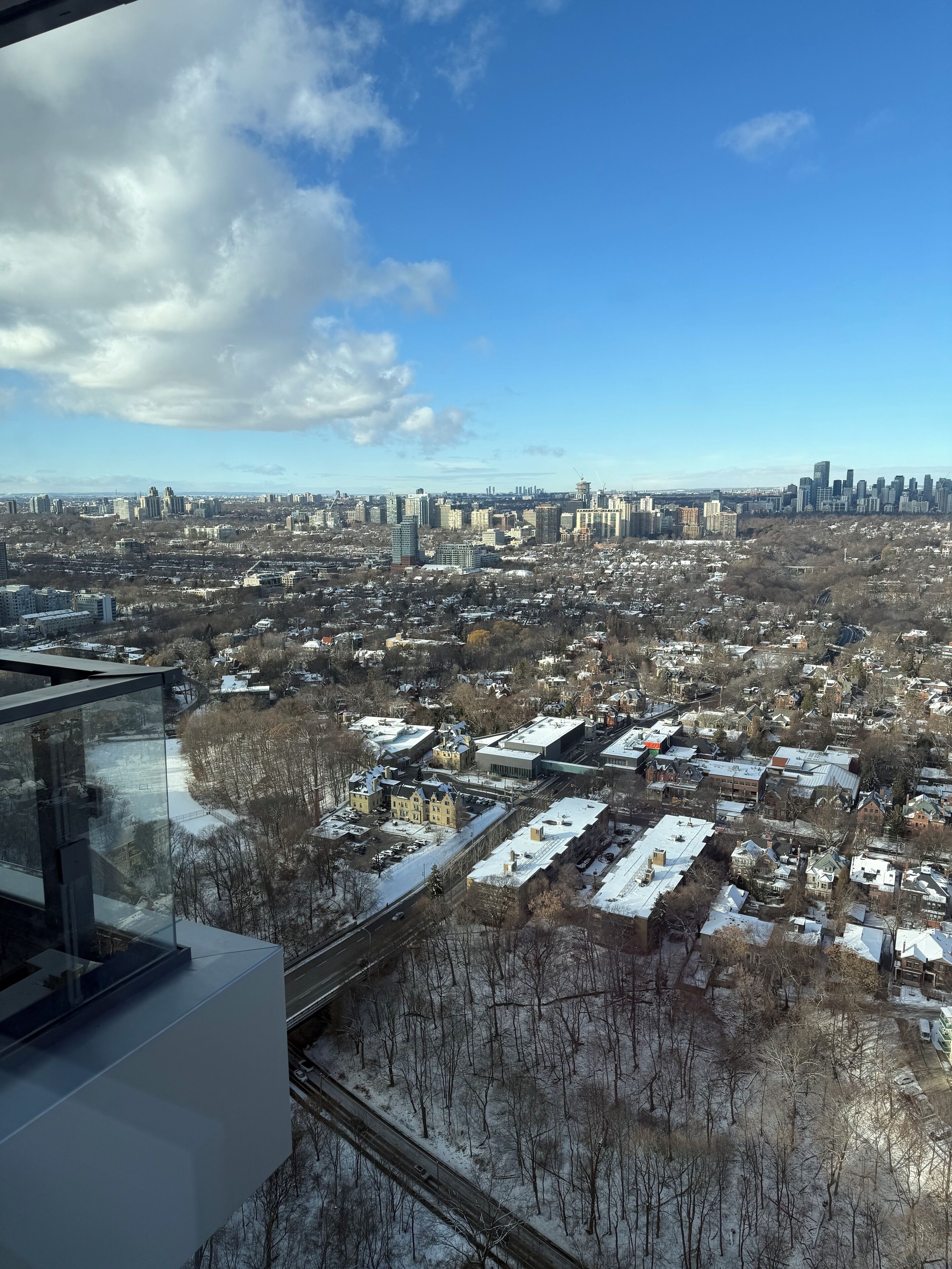 Vista panorámica de un paisaje urbano con edificios residenciales y comerciales, cielo despejado y suelo cubierto de nieve.