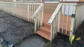 Ein eingeschossiges Gebäude mit einer Holzterrasse und einer Treppe, die zu einer Tür mit der Nummer 8 führt.