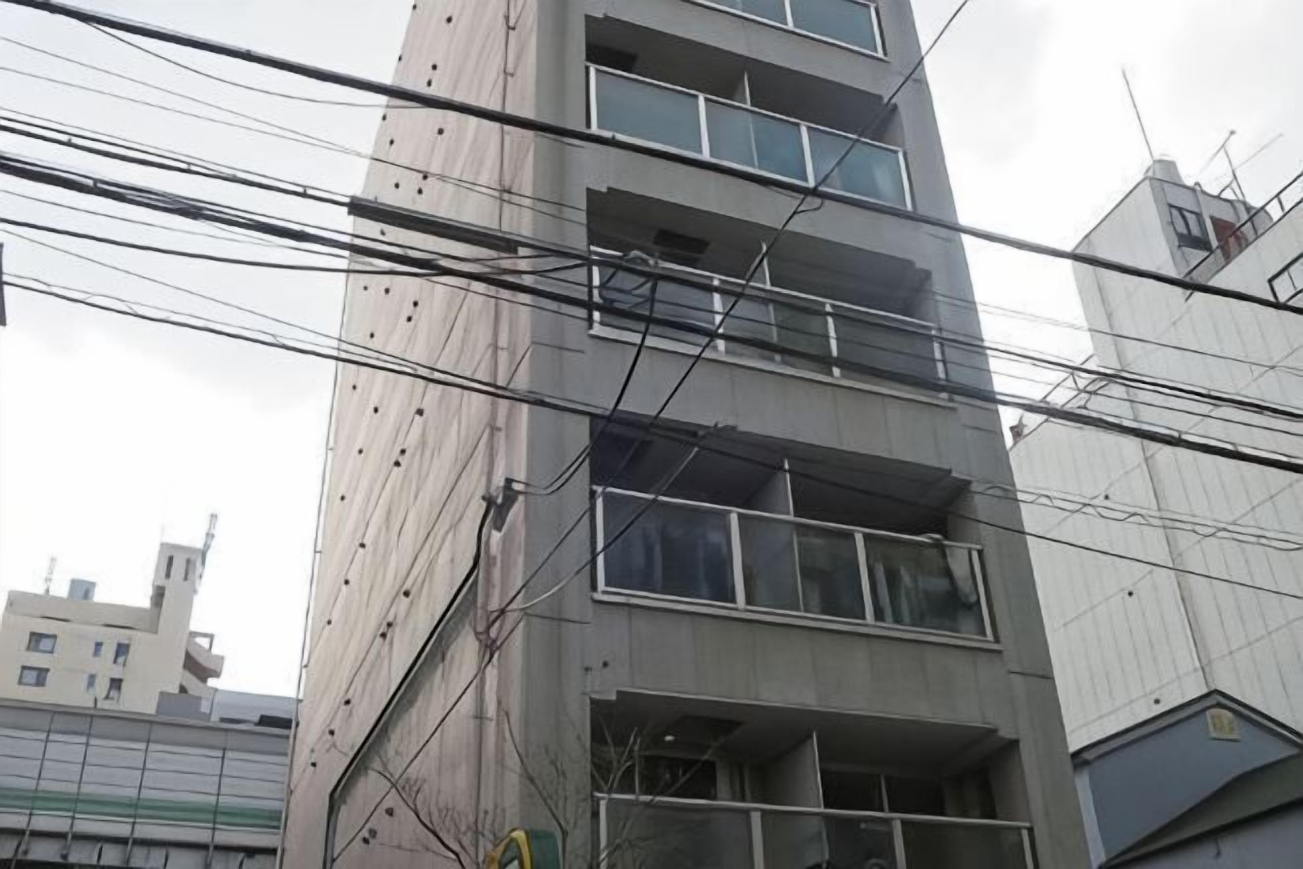 A multi-story building with visible balconies and a series of windows.