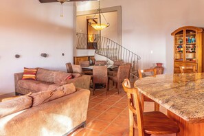 A spacious living area with a dining table, sofas, and a kitchen in the background.