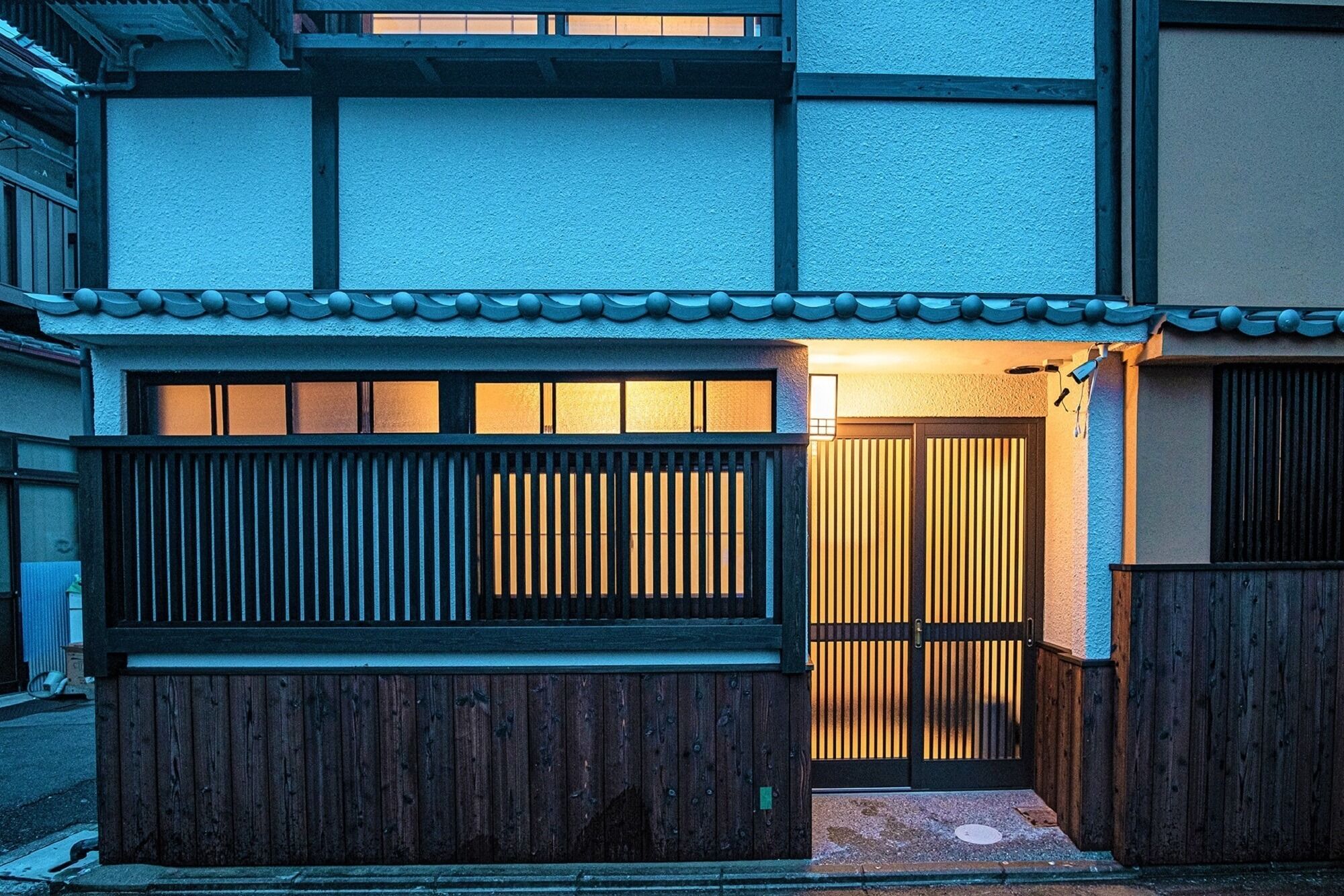 Ett traditionellt japanskt hus med en träport, ett tak täckt med tegelpannor och en skjutdörr.