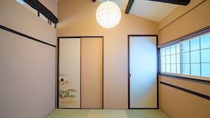 Una habitación japonesa tradicional con suelo de tatami, puertas correderas y vistas por una ventana.
