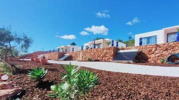 A coastal hotel with a stone facade, a paved walkway, and a clear blue sky.