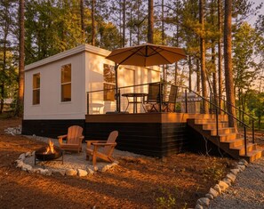 Una cabaña con terraza, mobiliario exterior y una chimenea.