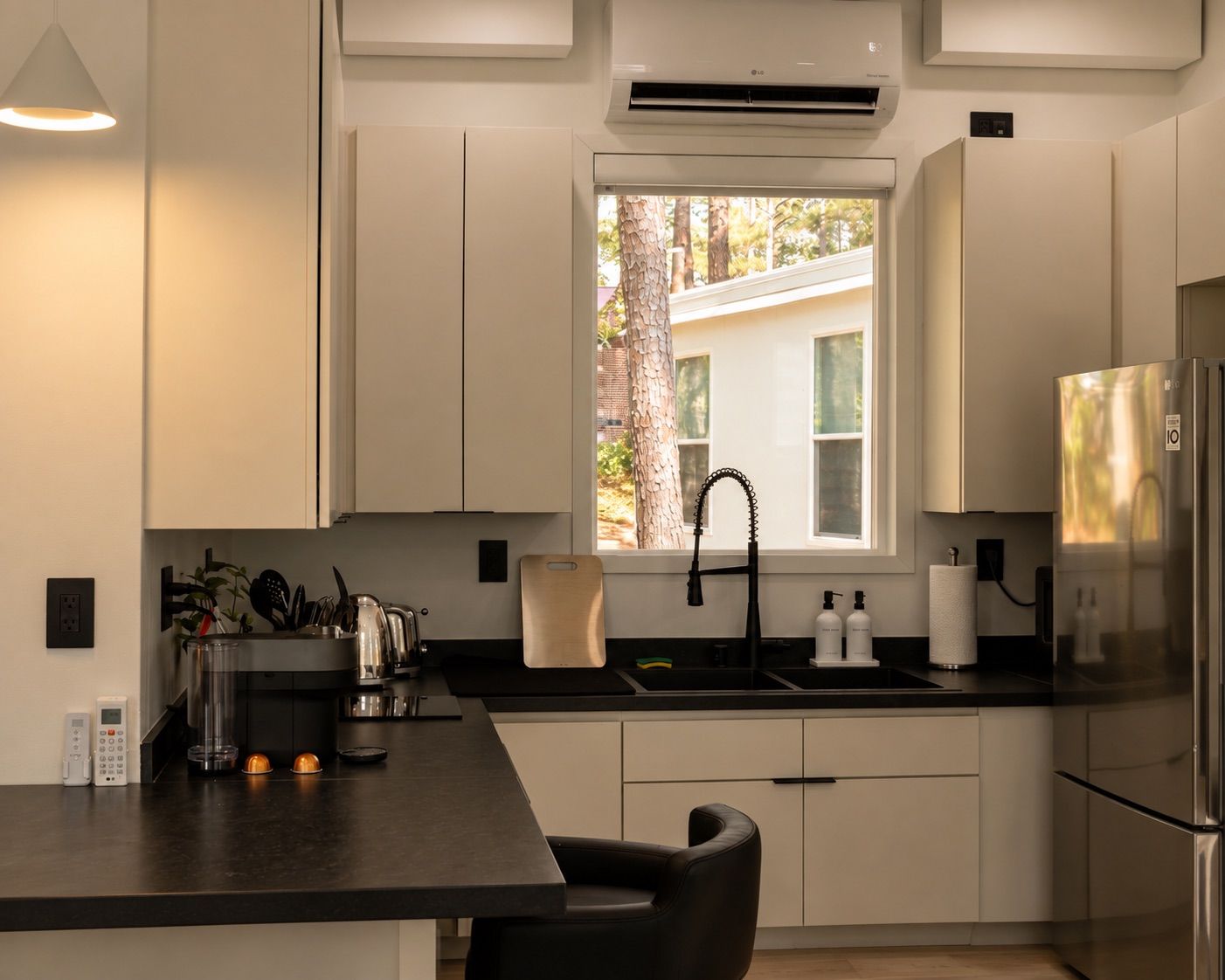 A modern kitchen with a window, stainless steel appliances, and a black countertop.