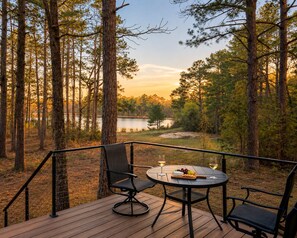 Una terraza con mesa y sillas que da a un lago rodeado de árboles.