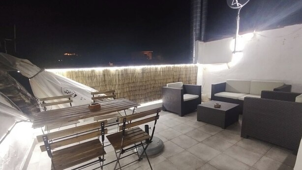 En udendørs terrasse med spisebord, stole og sofa.