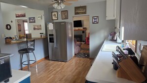 A modern kitchen with a stainless steel refrigerator, wooden bar counter, and a seating area with a chair.