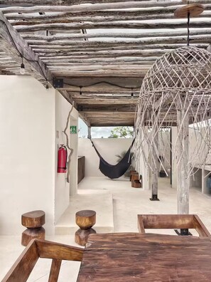 A rustic interior with a hammock, wooden furniture, and a fire extinguisher. - PH Cálido con Rooftop + Alberca en Tulum Centro (Tulum)