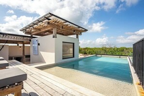 A modern outdoor pool area with a pergola, a covered seating area, and a clear view of the surrounding landscape. - Loft Bohemio con Alberca en Rooftop y WiFi Rápido (Tulum)