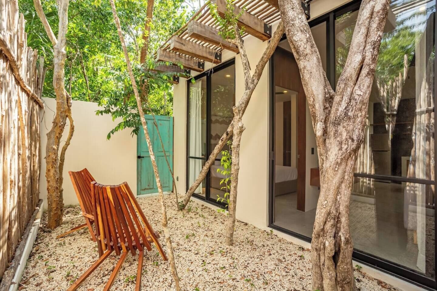 A wooden chair in a covered outdoor area with trees and a building in the background.